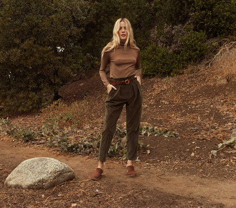 A person wearing stylish pants shorts stands confidently outdoors among greenery.