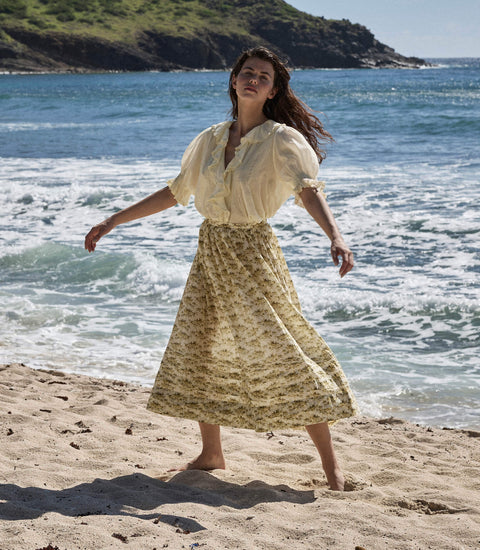 A model wearing a beautiful yellow floral skirt at the beach, showcasing stylish Skirts for summer fashion.